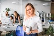 © pantovich - Beautiful girl with a glass of coffee standing in the office