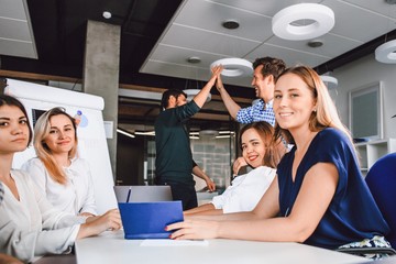Wall Mural - Business people work together in an office interior. Colleagues or employees give five to each other after concluding a contract between the companies.