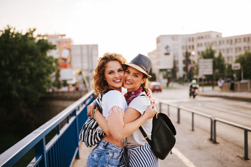 Portrait of a two gorgeous young female friends hugging while standing in the city. Summer music festival concept.