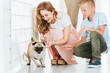 © LIGHTFIELD STUDIOS - happy mother palming adopted pug dog in corridor of at animals shelter