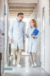 © LIGHTFIELD STUDIOS - veterinarians in white coats walking with clipboards in veterinary clinic and looking at each other