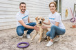 © LIGHTFIELD STUDIOS - smiling volunteers of animals shelter squatting and palming labrador