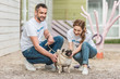 © LIGHTFIELD STUDIOS - two volunteers of animals shelter palming pug dog on yard