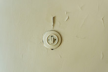 Old Plastic Light Switch On A Common Walled Wall Covered With A Thick Layer Of Oil Paint Inside A Fresh Room