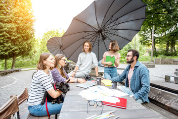 Wall Mural - Young friends having fun talking together during a studying outdoors in the park