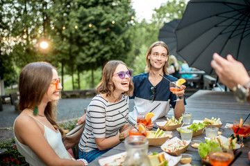 Young friends having fun together with snacks and drinks during the evening light outdoors in the park cafe