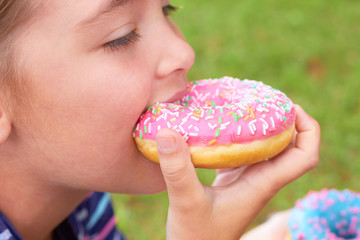 Cute little girl is eating donuts.