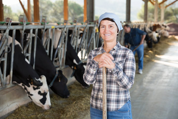 woman farmer posing on background of cows in stall