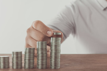 Wall Mural - cropped image of man stacking coins on wooden surface, saving concept