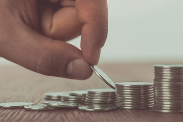 Wall Mural - Cropped image of man stacking coins on wooden table, saving concept