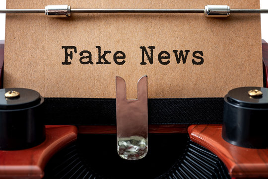 The dishonest media and unreliable newspapers concept with close up on a brown vintage typewriter with the text - fake news - written on yellow grungy cardboard like paper