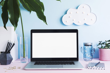 Wall Mural - Stylish and creative desk with laptop mock up screen, office accessories, tropical leaf, cup and hanging cloud. Blue background wall. Design home office interior. 