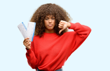 Poster - African american woman holding airline boarding pass tickets with angry face, negative sign showing dislike with thumbs down, rejection concept