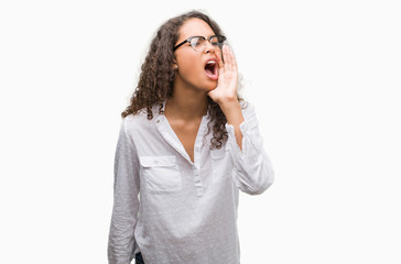 Beautiful young hispanic woman shouting and screaming loud to side with hand on mouth. Communication concept.