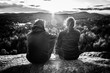 © Valmedia - Cute couple sitting on the top of a mountain, facing the sun with flares between them, seen from behind, black and white