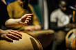 Woman's hands playing calabash with blurry musicians playing african instruments live on stage
