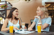 © fotofabrika - Two beautiful young girls sitting by the table in cafe