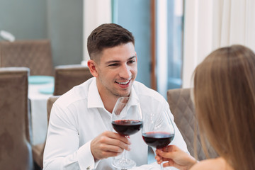 Wall Mural - Beautiful young couple with glasses of red wine in luxury restaurant