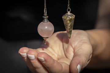 Two Beautiful Crystal Pendulums Hanging over a Hand