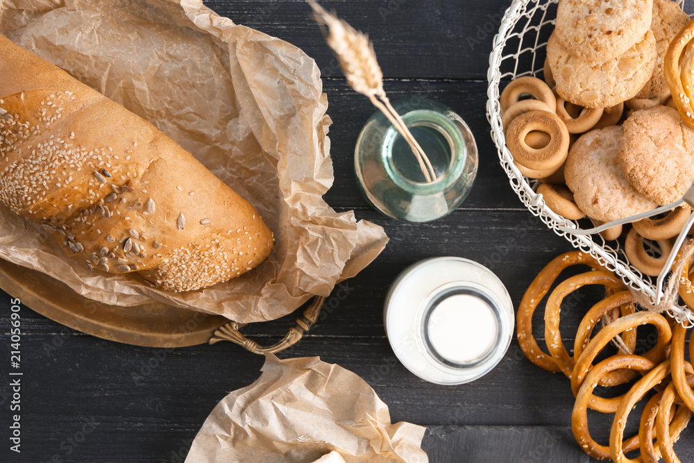 Flat lay composition with different bakery products, butter and milk on wooden background