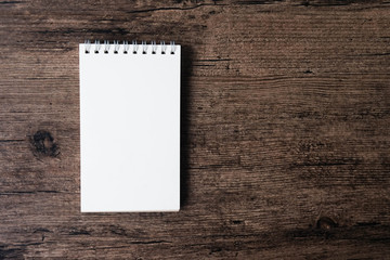 Top view image of open notebook with blank page on the wooden table..