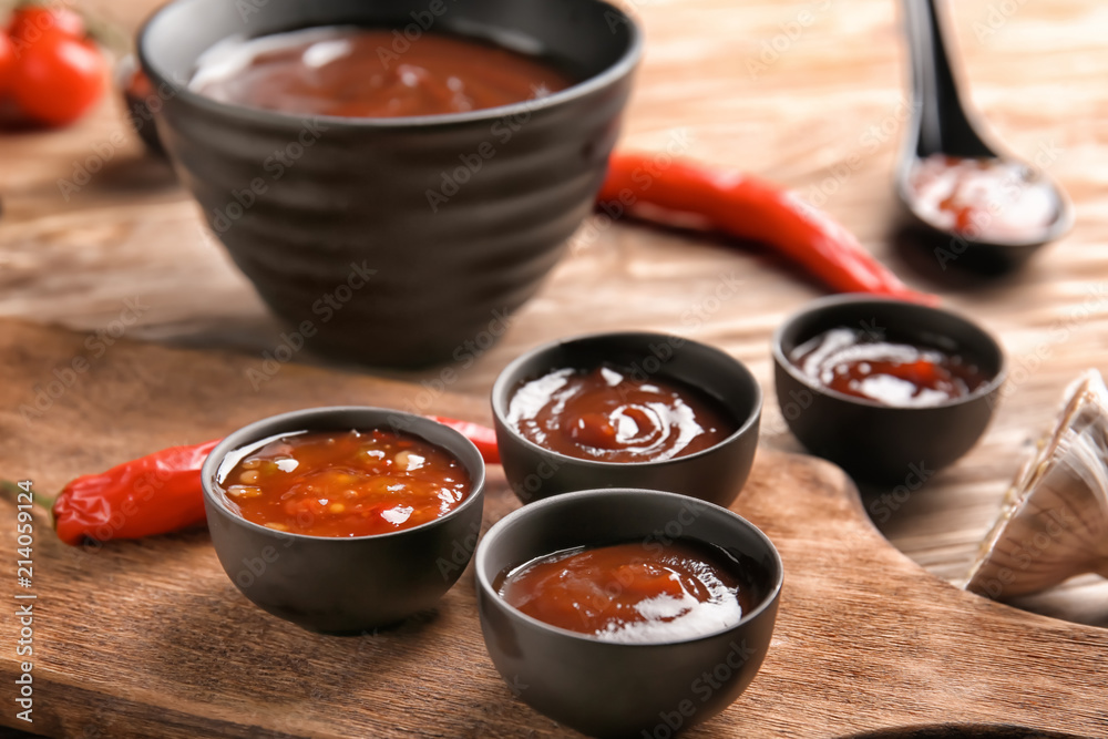 Bowls with barbecue sauce on wooden board