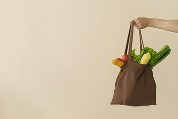 man hand holding cotton grocery bag with vegetables