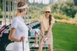 © LIGHTFIELD STUDIOS - selective focus of smiling woman in sunglasses playing golf together with friends at golf course