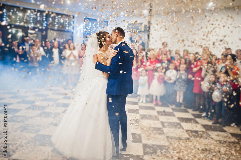 Gorgeous wedding couple performing their first dance with confetti, colorful lights and fireworks. - obrazy, fototapety, plakaty 
