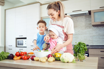 Mother and children are cooking in the kitchen.