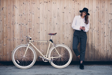 Wall Mural - Portrait of beautiful brunette holding bicycle. Wooden background.