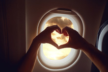 The Concept Of Travel. Hands In The Shape Of Heart  On The Background Of The Airplane Window.