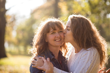 mother being kissed by her teen daughter
