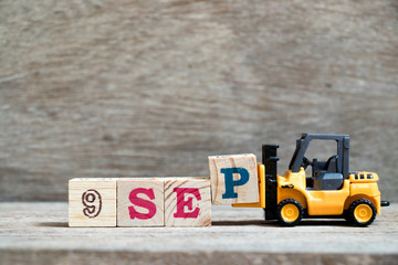 Wall Mural - Toy forklift hold block P to complete word 9 sep on wood background (Concept for calendar date in month September)