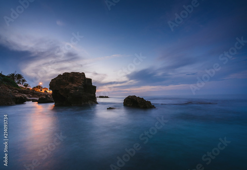 Fotografie, Obraz Sunset on the beach among the rocks near the city of Denia