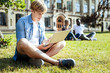 © Viacheslav Yakobchuk - Completing task. Serious student crossing legs while sitting on the grass and preparing project