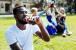 © Viacheslav Yakobchuk - Favorite drink. Handsome African American gentleman looking into vacancy with a cheerful smile on her face while drinking sparking water outdoors.