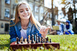© Viacheslav Yakobchuk - This is so relaxing. Beautiful blonde girl grinning broadly while lying on grass enjoying chess game outdoors.