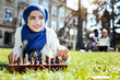 © Viacheslav Yakobchuk - What if. Extremely pretty Muslim girl thinking of something pleasant while lying on grass and playing chess alone.
