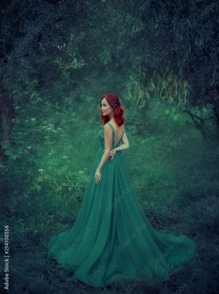 Red-haired girl in a green, emerald, luxurious dress in the floor, with an  open back