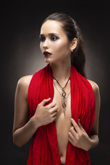 Wall Mural - Beautiful brunette topless girl model, covering her naked breast with a red scarf and wearing a modern necklace on the deep decollete.