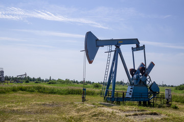 The beam pumping unit is homework, sunset in oil field. Oil pump oil rig energy industrial machine for petroleum. The pumping unit as the  pump installed on a well. Equipment of oil fields.