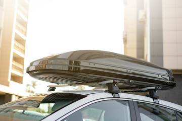 long black trunk on the roof of a white car. Travel and accessories for transportation.