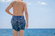 © stone36 - Close-up teenage boy in swimming shorts standing on the beach pier on the sea shore, ready to dive.