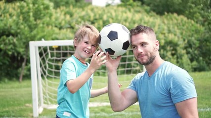 Wall Mural - Man with child playing football outside on field