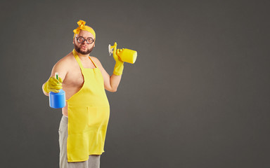 Funny fat cleaning man in an apron on cleaning on a background for text.