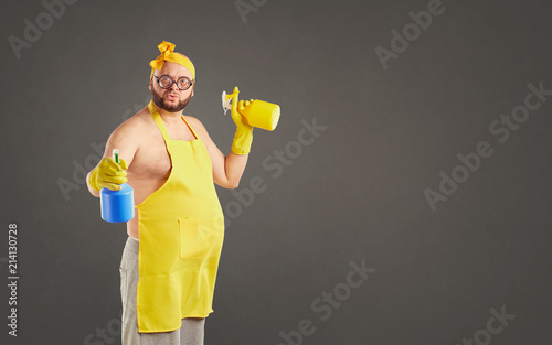 Cuadros en Lienzo Funny fat cleaning man in an apron on cleaning on a background for text