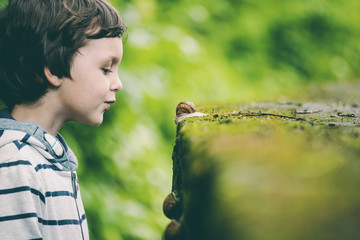 The boy is looking at the snail.