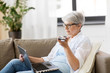 © Syda Productions - technology, old age and people concept - happy senior woman in glasses with laptop computer and smartphone using voice command recorder at home