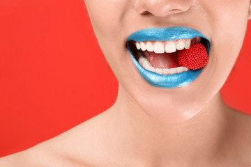 Sticker - Beautiful young woman with creative makeup and candy in mouth on color background, closeup